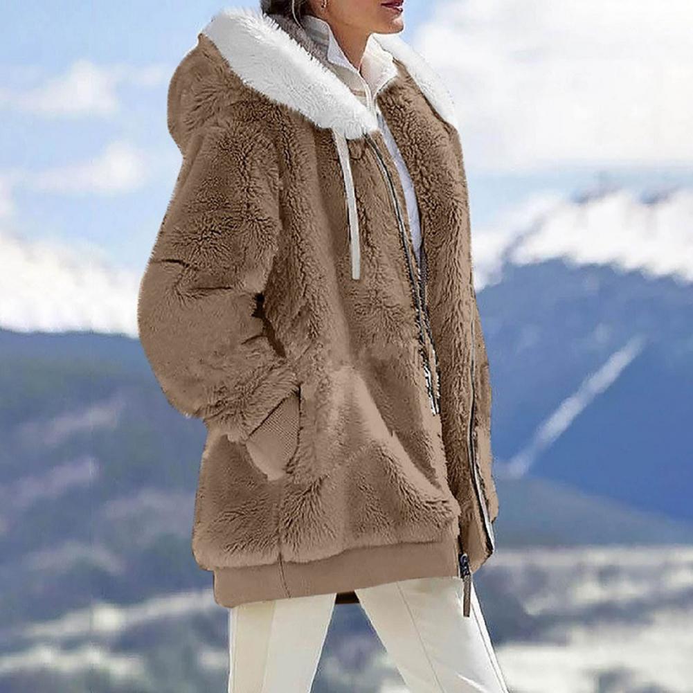 Stylish women's beige plush hooded jacket with fur collar, perfect for winter outings in a scenic mountain setting.